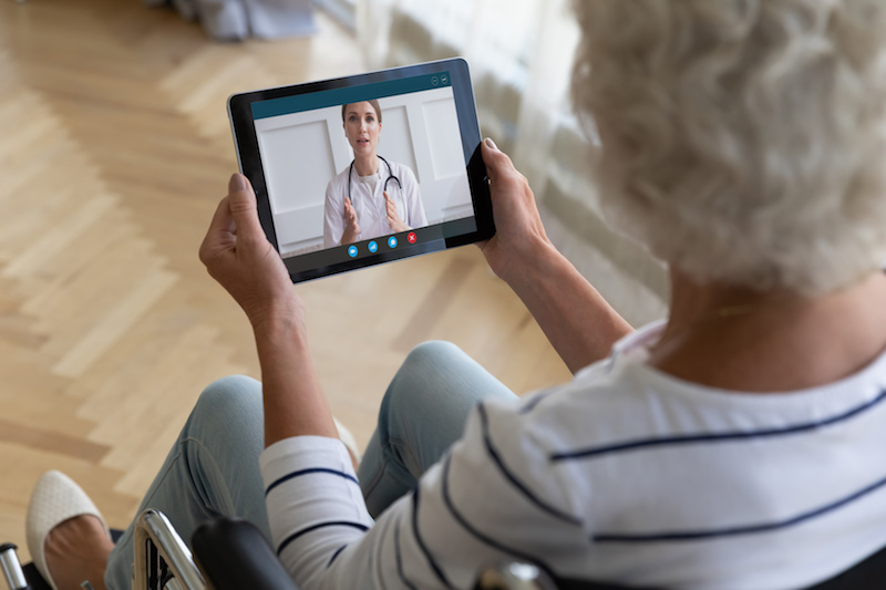 Top view close up disabled older woman sitting in wheelchair, using computer tablet, looking at screen, forgot password, mature female holding electronic device in hands, problem with memory