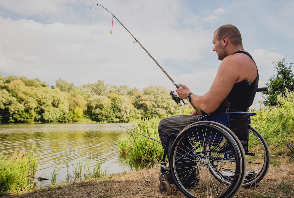 Handicapped man fishing at a lake. Wheelchair. Camping. Summertime
