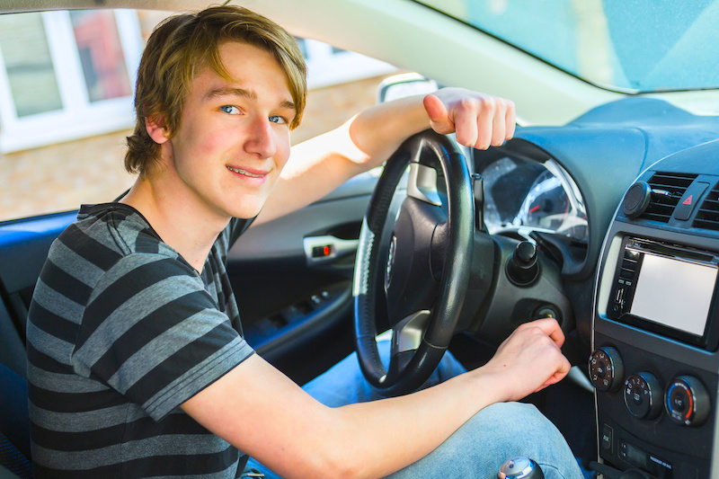 A Teenage boy and new driver behind wheel of his car